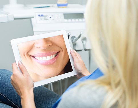 Woman looking at her virtual smile design on tablet computer