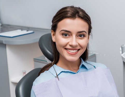 Female dental patient sitting in chair and smiling 