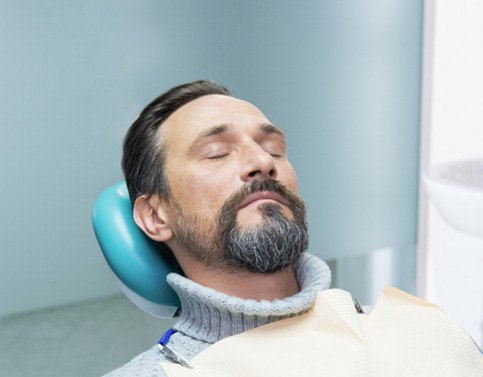 Male dental patient in sweater asleep in dental chair 