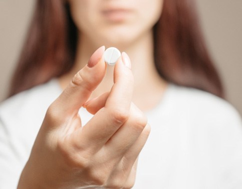 Woman holding pill for oral conscious sedation in Edison, NJ