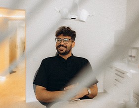 Patient with black glasses smiling in treatment chair
