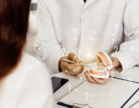 A dentist holding a mouth mold and showing a patient how All-On-4 dental implants work