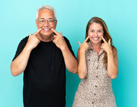 Happy, mature couple pointing at their teeth