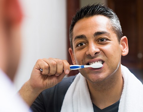 Man brushing his teeth after dental crown restoration