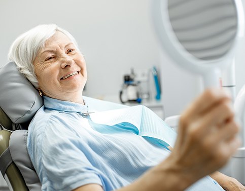 Woman looking at smile after denture tooth replacement