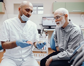 An older man talking to a dentist about dentures