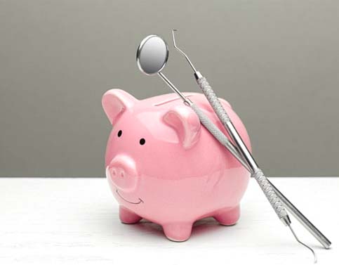 two dental instruments leaning against a pink piggy bank