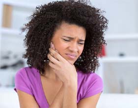 woman holding the side of her face in pain