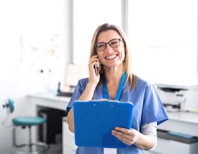 dental team member talking on the phone and holding a clipboard