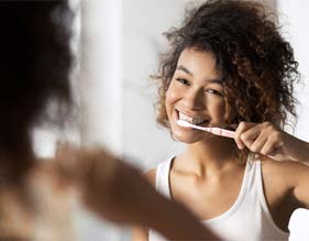 young woman brushing teeth in bathroom