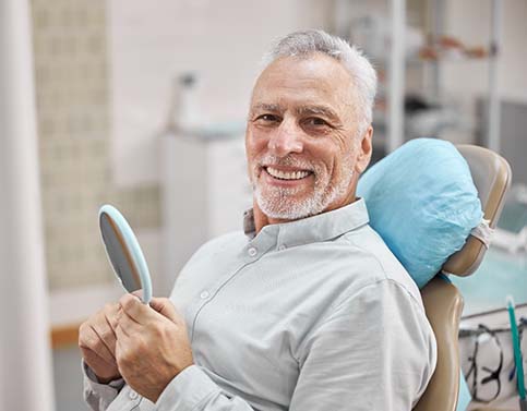 senior man smiling while sitting in the dental chair