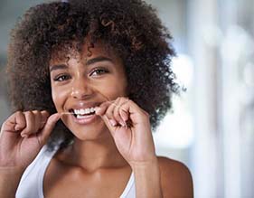 woman smiling while flossing