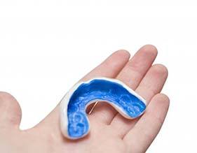 person holding a blue mouthguard in their hand