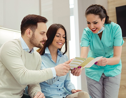 Dental team member showing patients dental insurance paperwork