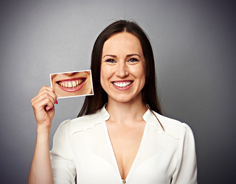 Smiling patient holding “before” picture taken prior to visiting Edison cosmetic dentist