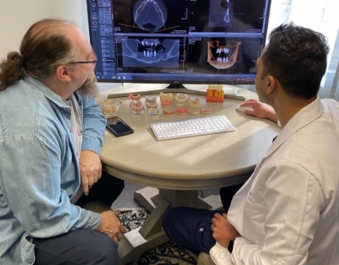 Dentist and patient looking at digital smile design on computer