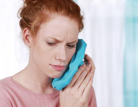 a patient applying a cold compress to her cheek