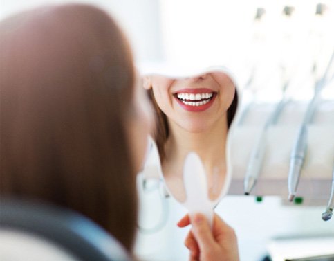 a patient inspecting their teeth in a mirror