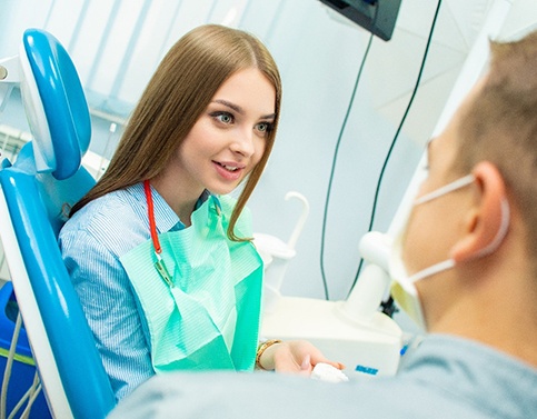 Young woman talking to dentist before procedure