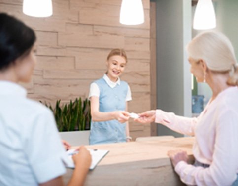 Smiling dental receptionist taking credit card from patient