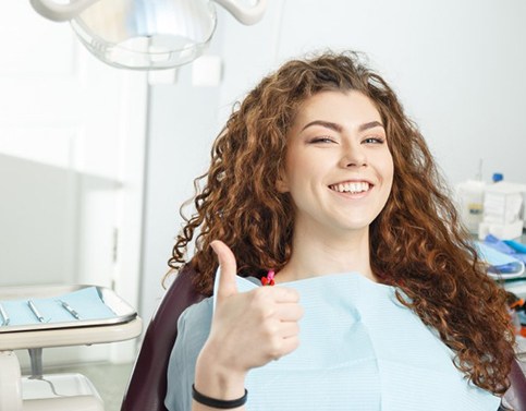 woman giving thumbs up in dental chair after getting porcelain veneers in Edison 