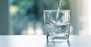 Water being poured into a glass that is sitting on a counter