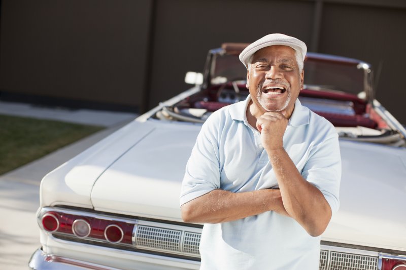 an older man standing next to a car and smiling thanks to his dental implants in Edison