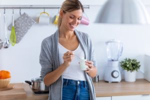 Woman eating yogurt after wisdom tooth extraction.