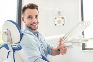 smiling man giving thumbs up in dental chair