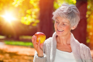 a patient with dentures holding an apple