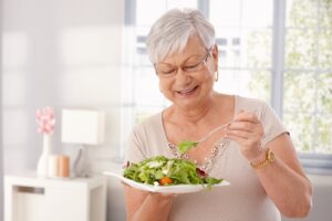 older woman eating a salad while wearing dentures